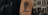 Pancarte "Tatoo" avec un crâne dessiné à la craie dans une petite rue dalée. Une personne est assise sur un banc devant le studio de tatouages.
